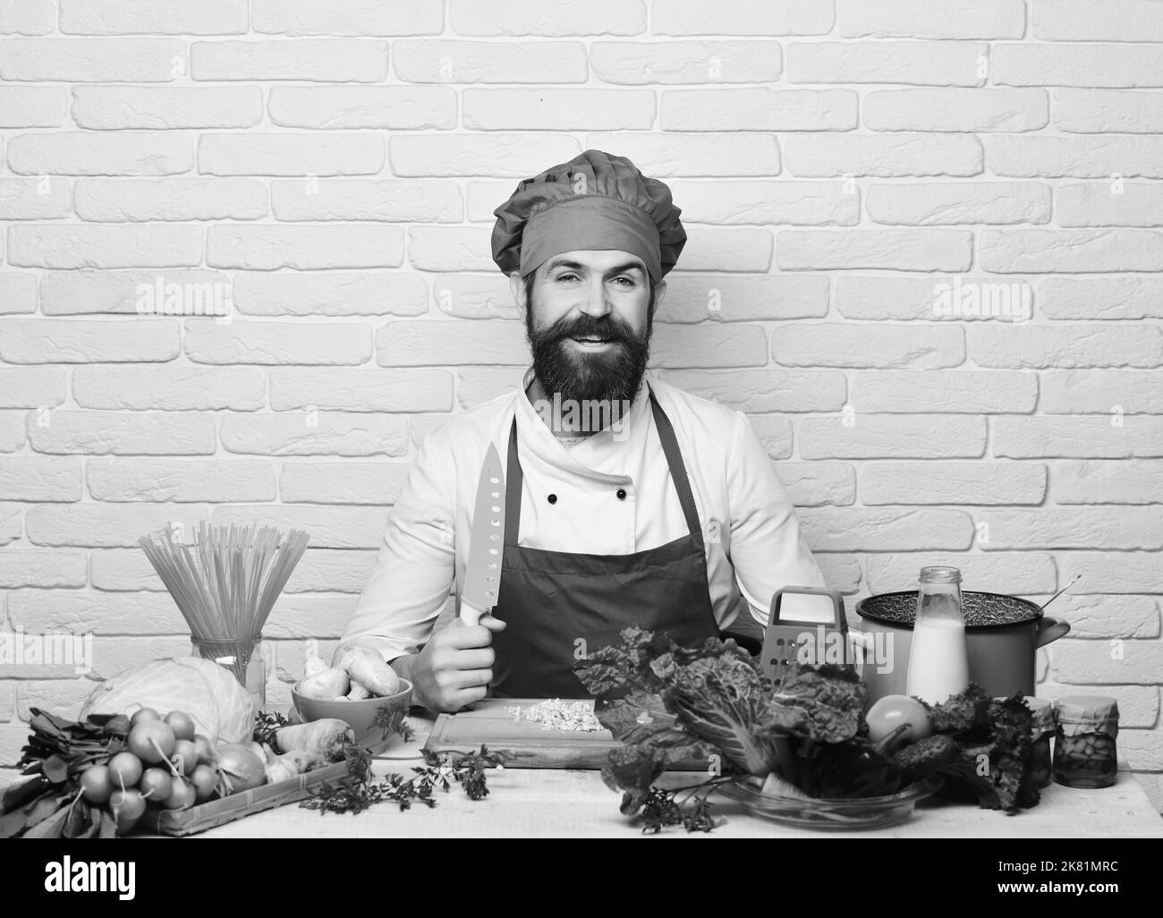 Cuisine du restaurant. Un homme avec une barbe tient le couteau sur fond blanc Banque D'Images