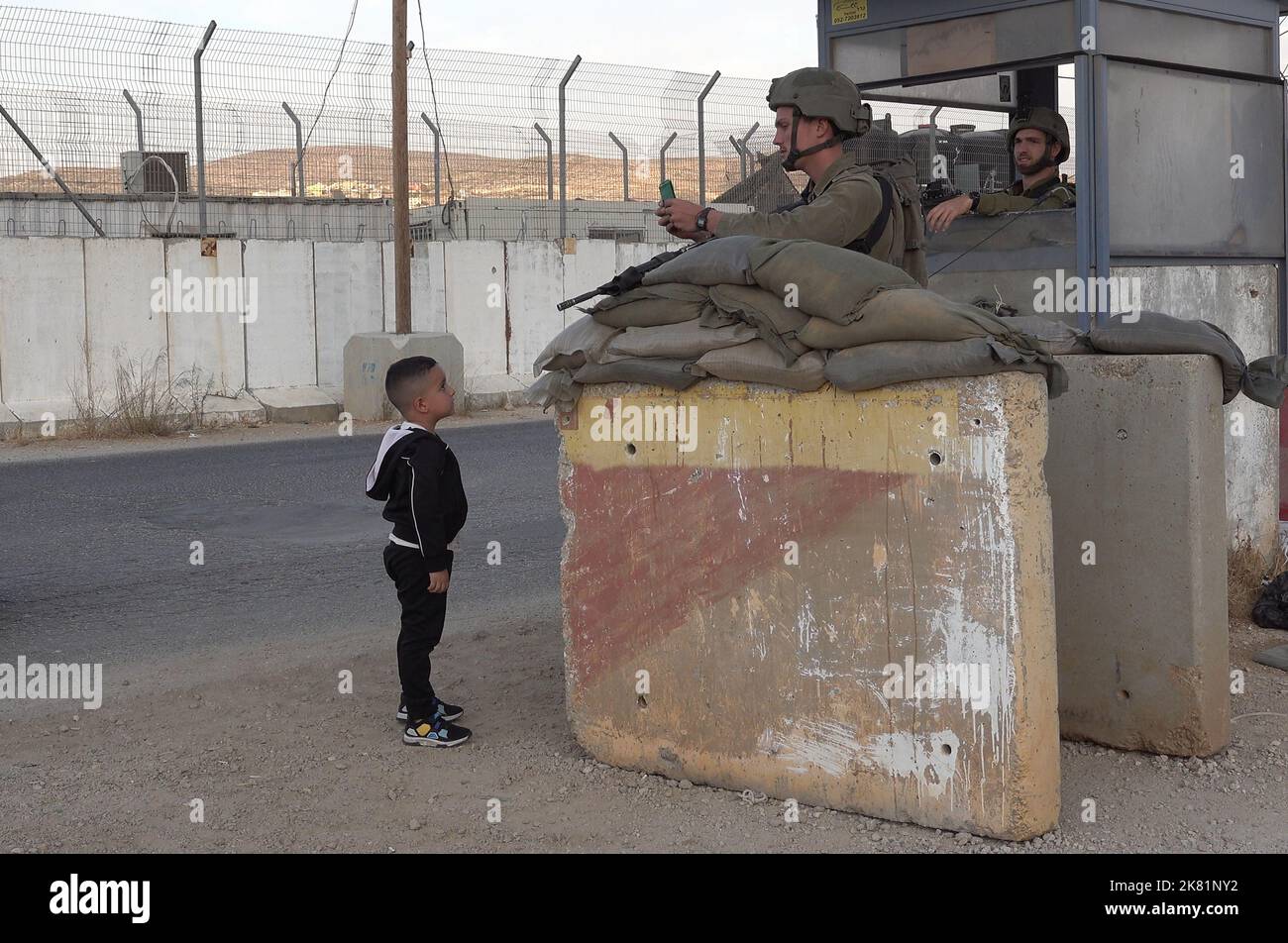 NAPLOUSE, CISJORDANIE - OCTOBRE 19 : les soldats israéliens gardent derrière des blocs de béton tandis qu'un jeune garçon palestinien montre la carte d'identité de ses parents au point de contrôle militaire Beit Furik sur 19 octobre 2022, situé à l'entrée est de Naplouse, en Cisjordanie. Les forces israéliennes ont imposé un blocus continu sur la zone autour de Naplouse, dans un contexte de tensions accrues en Cisjordanie qui restreignent le mouvement d'environ 420 000 Palestiniens. Crédit : Eddie Gerald/Alay Live News Banque D'Images