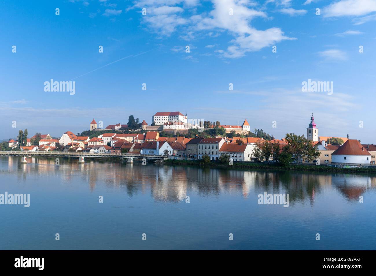 Ptuj, Slovénie - 11 octobre 2022 : panorama urbain de Ptuj avec le château perché et des reflets dans la rivière Drava Banque D'Images