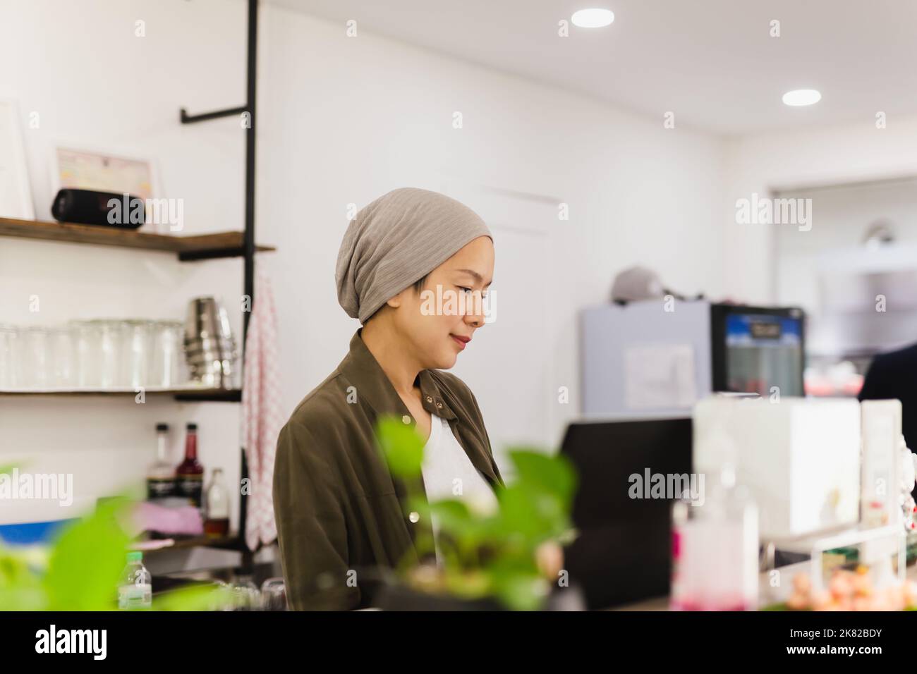 Femme propriétaire du restaurant debout au comptoir recevant les commandes. Banque D'Images