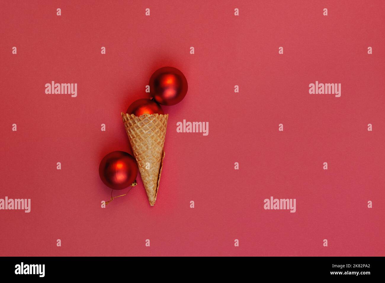 Flat Lay alternative glace crème boules de Noël dans le cône de gaufré sur fond rouge. Un coin roulé. Concept de fête des vacances d'hiver, composition festive avec vue sur le dessus. Banque D'Images