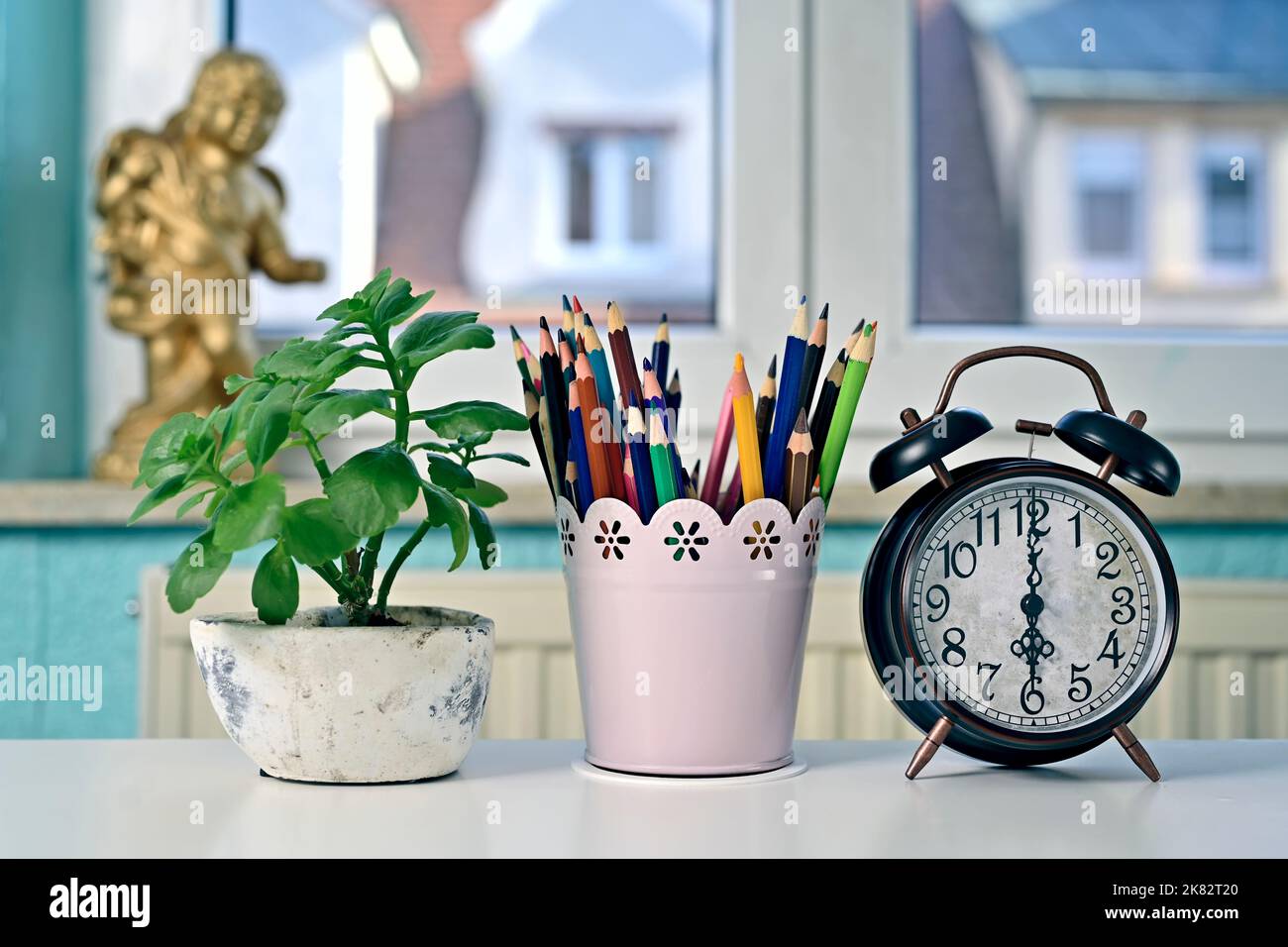 Réveil à côté des crayons colorés et des plantes en pot sur la table. Retour à l'école et concept de bureau à domicile. Banque D'Images
