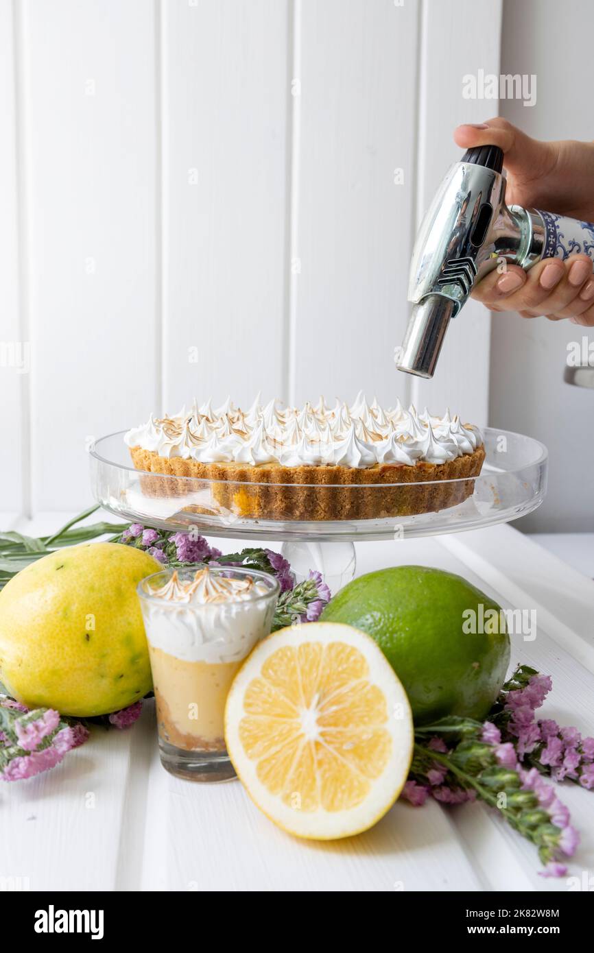 tenant un ustensile de cuisine pour colorer la crème sur un gâteau, dessert gastronomique, occupation de cuisine, table avec des fruits comme décoration Banque D'Images