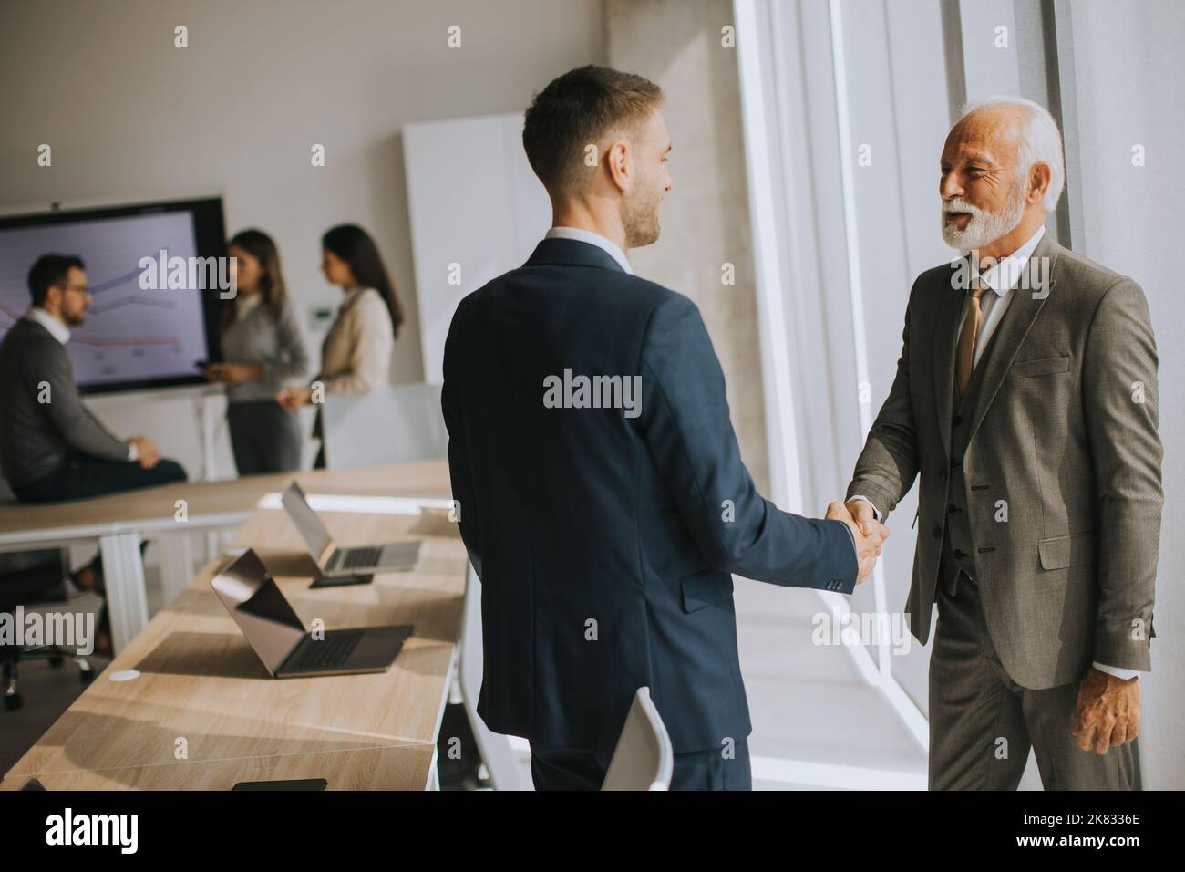 Homme d'affaires senior qui se fait le travail de liaison avec son jeune collègue au bureau Banque D'Images