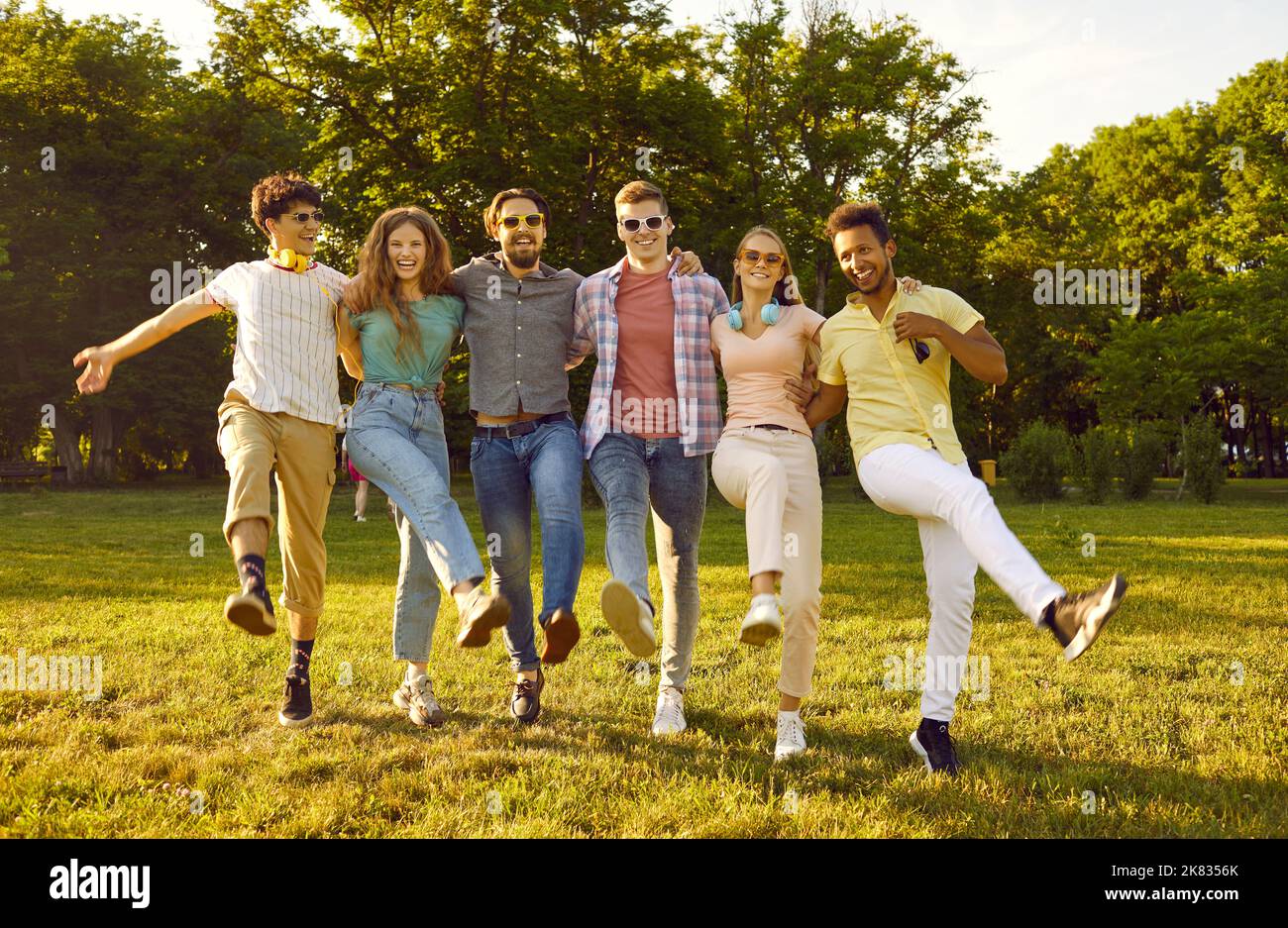 Groupe diversifié de jeunes joyeux et drôles ayant du plaisir dans le parc ensoleillé d'été tous ensemble Banque D'Images