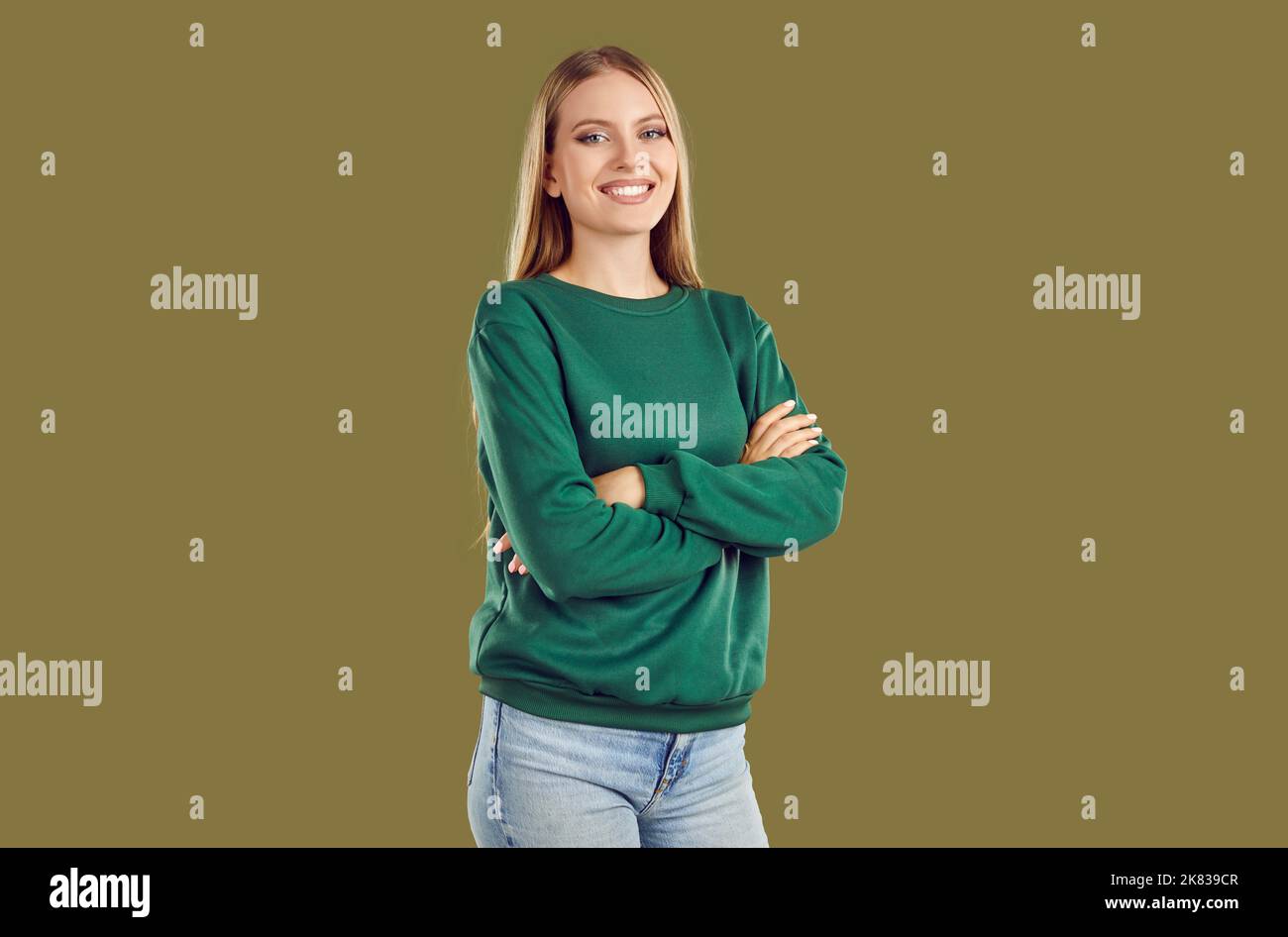Portrait d'une fille souriante en sweat-shirt vert pose sur fond kaki regardant l'appareil photo. Banque D'Images
