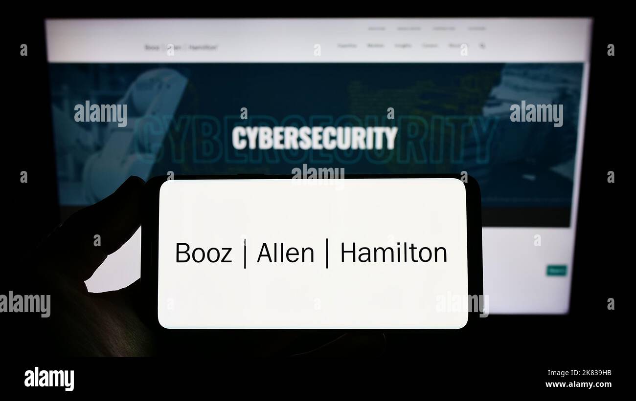 Personne tenant un smartphone avec le logo de la société de conseil américaine Booz Allen Hamilton Inc. À l'écran devant le site Web. Mise au point sur l'affichage du téléphone. Banque D'Images