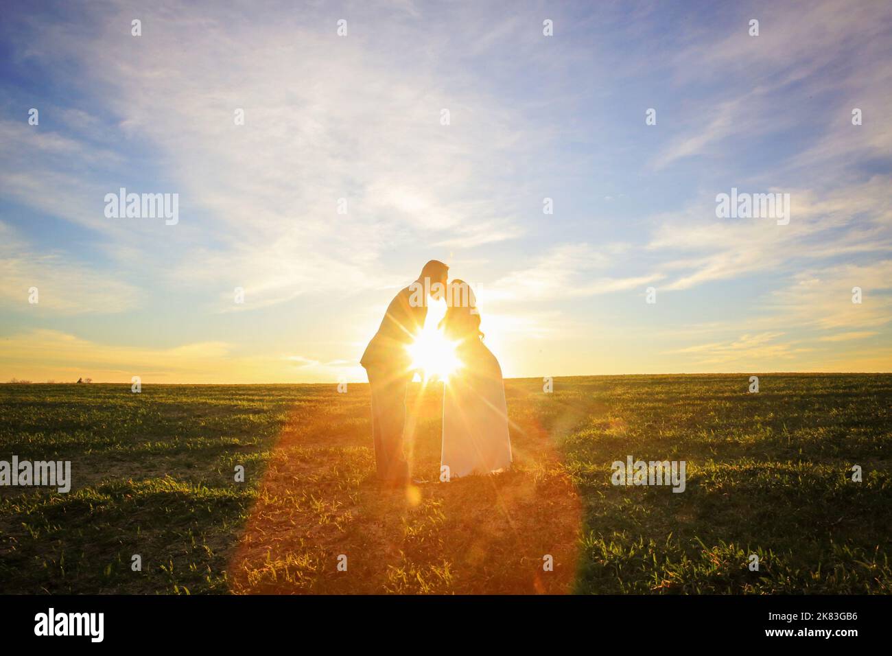 couple de mariage marchant sur la route de terre au coucher du soleil Banque D'Images