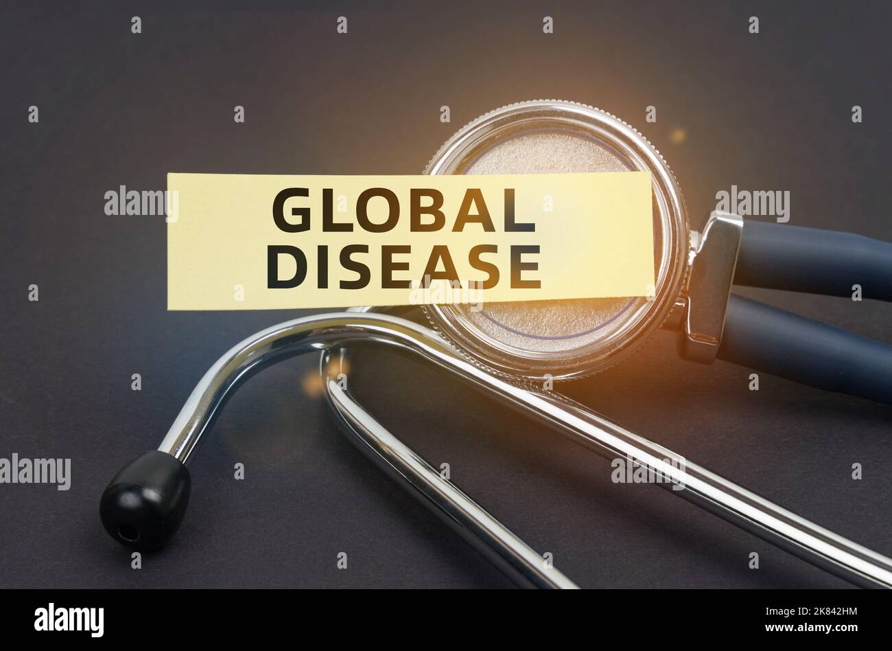 Concept de médecine. Sur un fond noir, un stéthoscope, sur lequel un autocollant avec l'inscription - MALADIE GLOBALE Banque D'Images