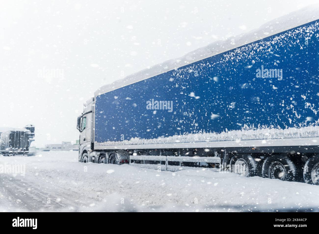 Gros camion semi-remorque commercial pris au piège de la neige sur une route à grande circulation fermée à une tempête de neige intense blizzard froid hiver jour. Véhicule utilitaire coincé en fonction Banque D'Images