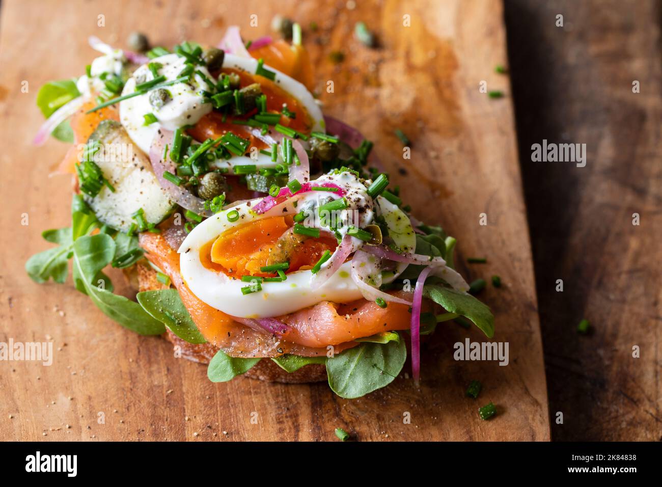 Sandwich ouvert avec saumon fumé, œuf, oignons marinés, crème sure et câpres Banque D'Images