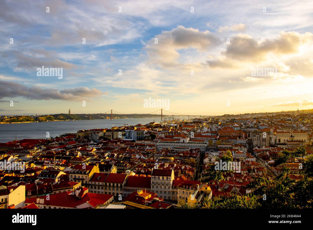 Paysage de la vieille ville de Lisbonne au coucher du soleil. Heure d'or à Lisbonne avec vue sur les toits rouges, le ciel bleu et le pont de 25 avril à une distance Banque D'Images