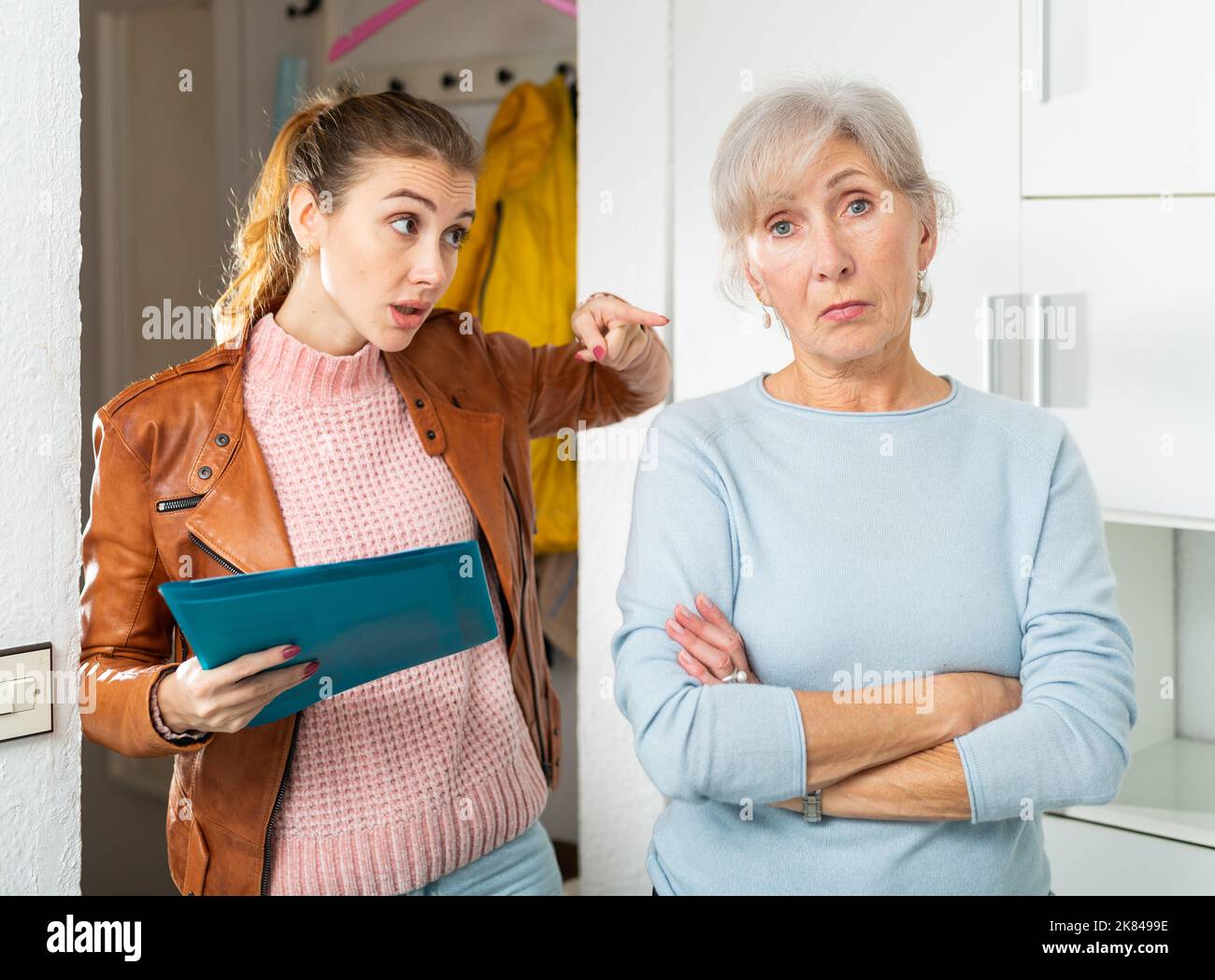 Femme âgée frustrée parlant à une femme collectrice de dette à la maison Banque D'Images