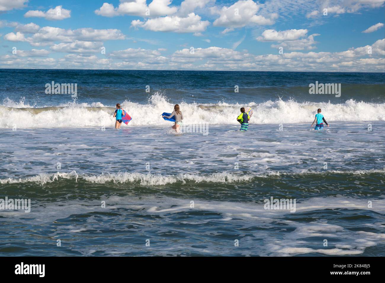Avon, Outer Banks, Caroline du Nord, USA. Les adolescents et pré-adolescents dans l'Atlantique avec leurs planches de surf. Banque D'Images