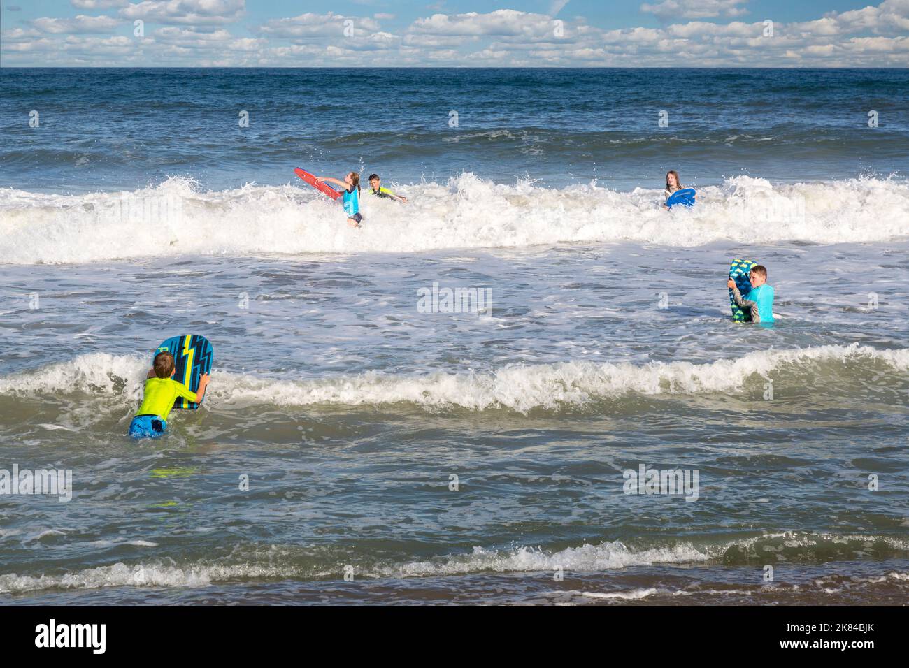 Avon, Outer Banks, Caroline du Nord, USA. Les adolescents et pré-adolescents dans l'Atlantique avec leurs planches de surf. Banque D'Images