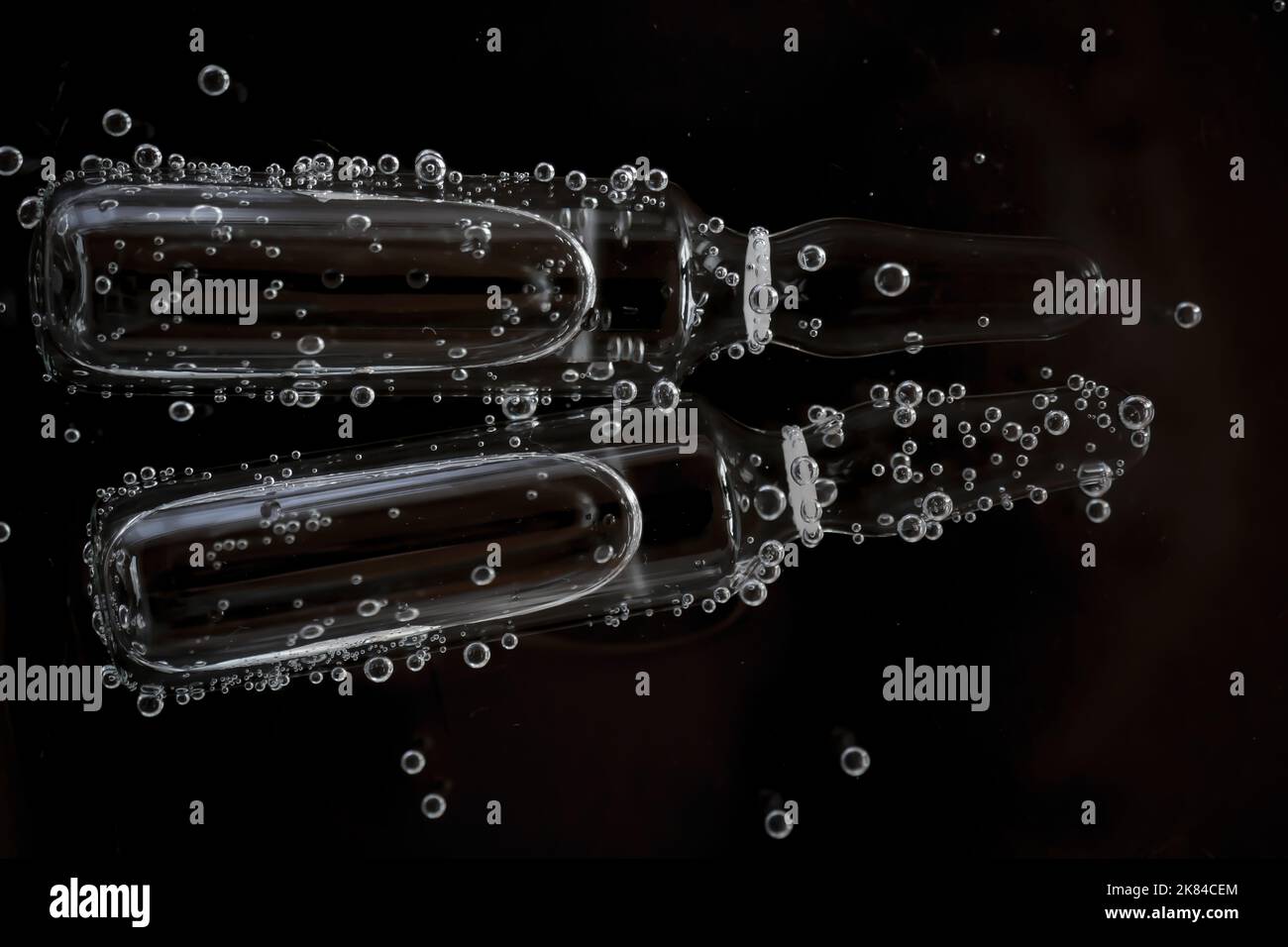 Acide hyaluronique en ampoules. Produits de beauté en ampoule.sérum de mésothérapie et de dermabrasion en ampoules.ampoules cosmétiques dans des bulles d'eau sur un noir Banque D'Images