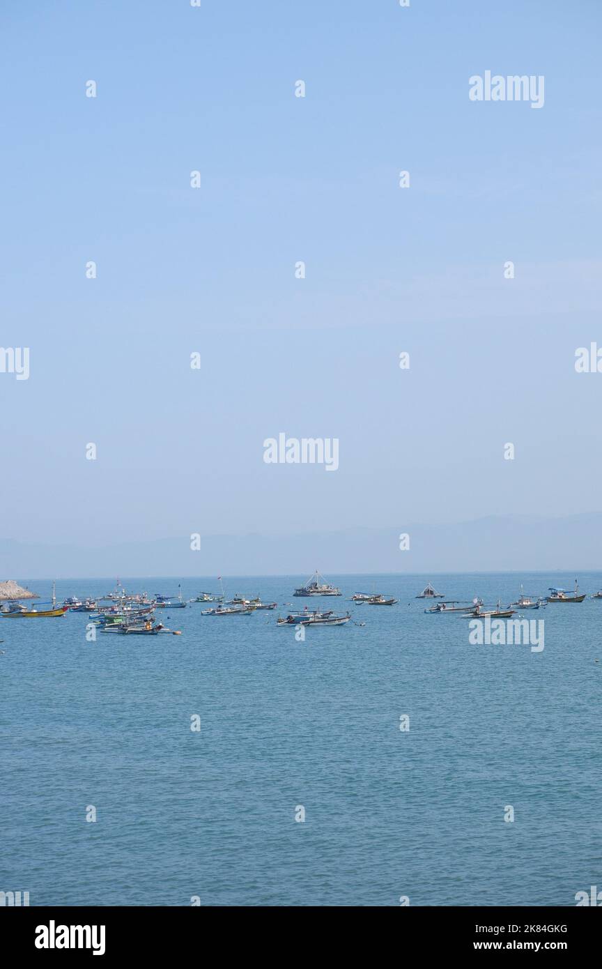 Un groupe de bateaux de pêche se prépare au milieu de la mer pour pêcher, avec des vues sur la montagne et le temps ensoleillé, les pêcheurs sont excités Banque D'Images