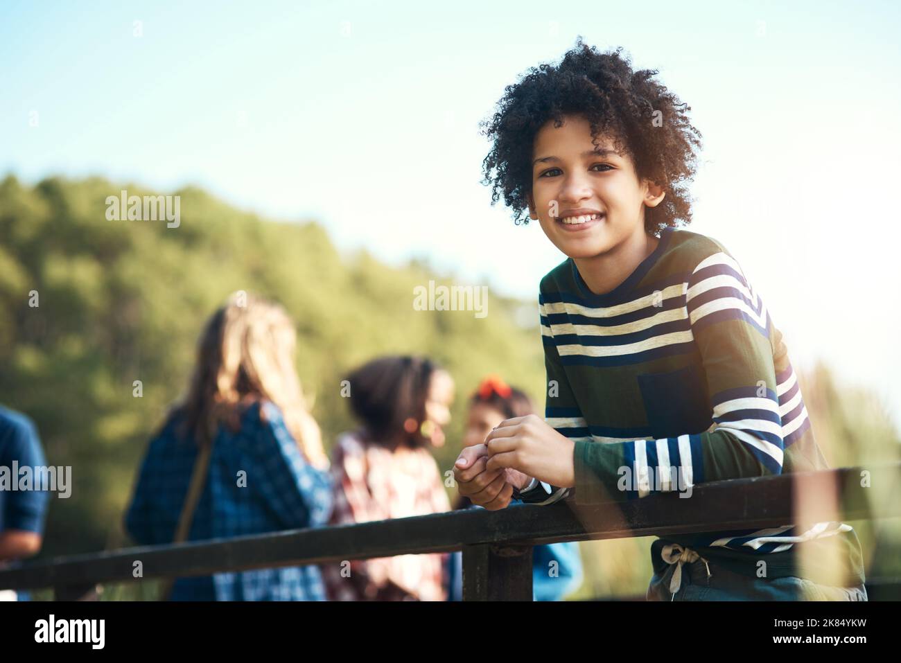 Le temps est trop beau pour s'asseoir à l'intérieur. Un adolescent debout sur un pont dans la nature au camp d'été. Banque D'Images