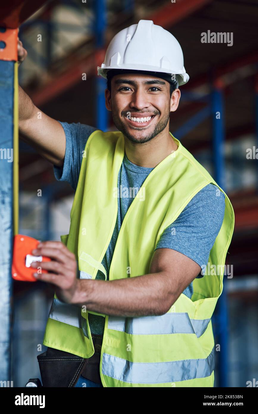 Je suis fier du travail que je fournit. Un jeune constructeur utilisant un ruban de mesure sur un chantier de construction. Banque D'Images