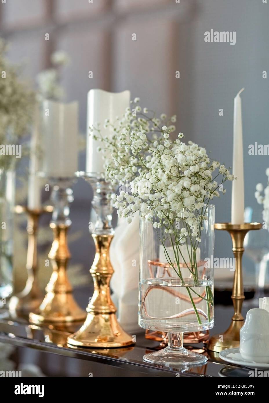 Porte-bougie en gros plan doré sur une table de luxe en verre miroir lors  d'un mariage moderne. Décoration de table festive. Fleurs, verre  transparent et décor doré, bougies Photo Stock - Alamy