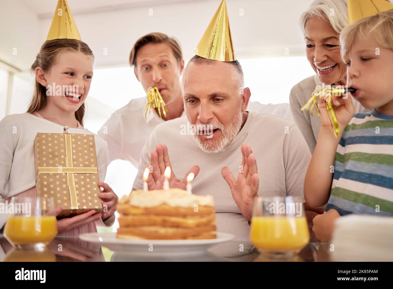 Gâteau d'anniversaire, célébration et grand-père avec des enfants de famille chantant, excités et célébrer ensemble. Personne âgée, homme âgé avec enfants, boîte cadeau Banque D'Images