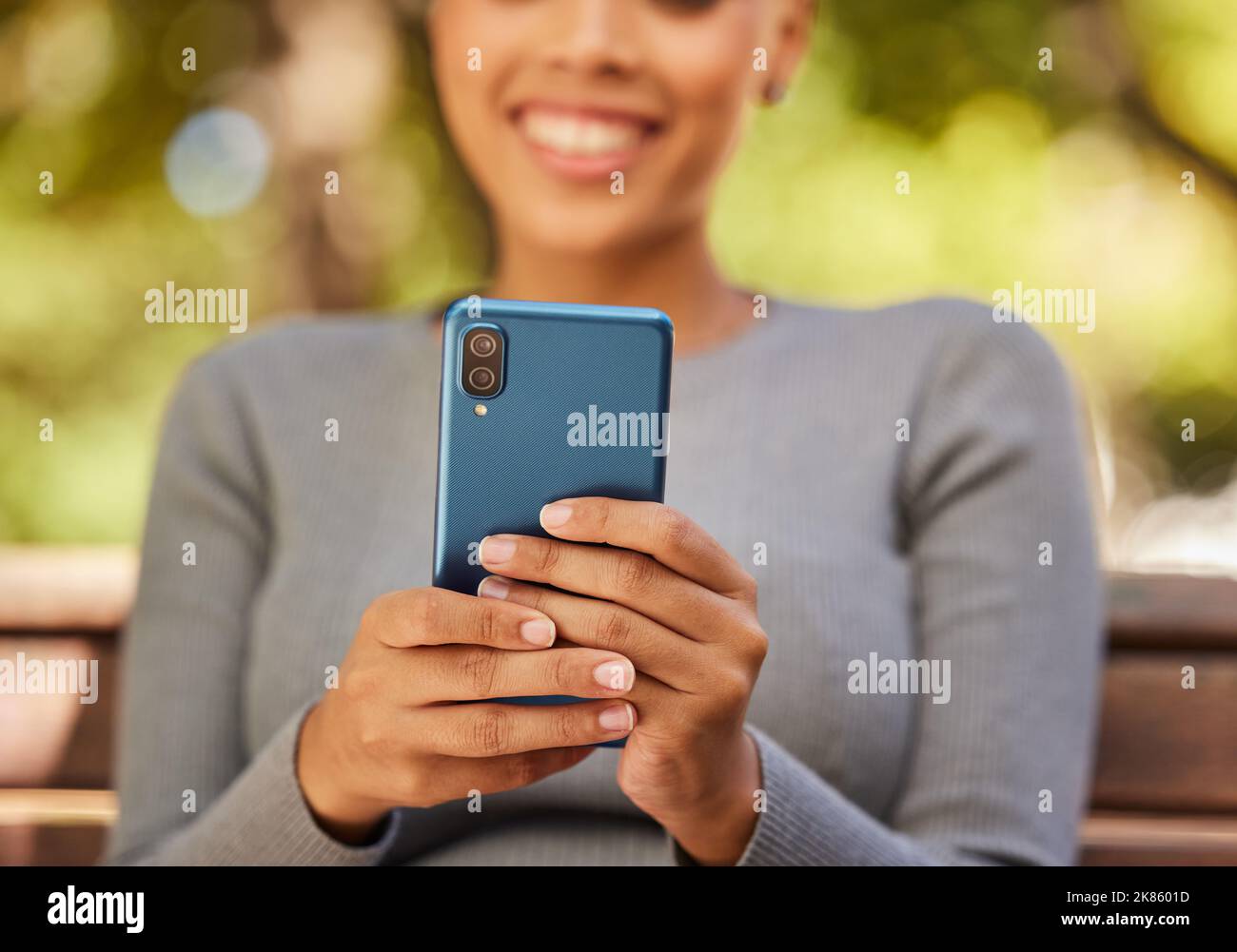 Smartphone, sourire et femme mains tout en diffusant dans un parc naturel, un abonnement en ligne ou un post sur les réseaux sociaux. 5G communication, sourire et bonne fille Banque D'Images