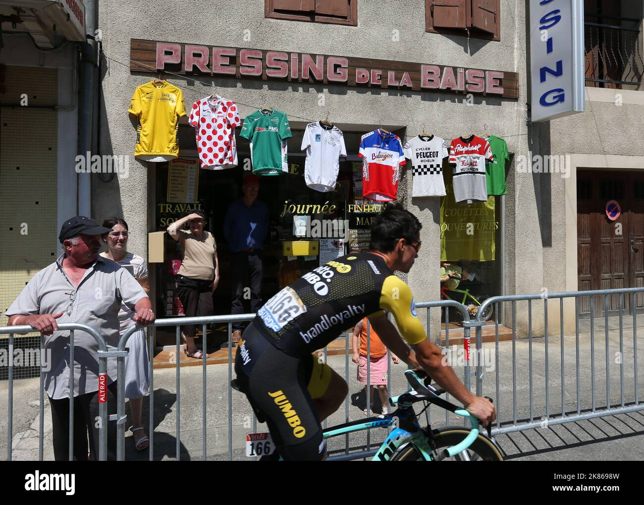 Primoz Roglic (LottoJumbo NL) passe devant une boutique avec une collection de maillots de cyclisme vintage Banque D'Images