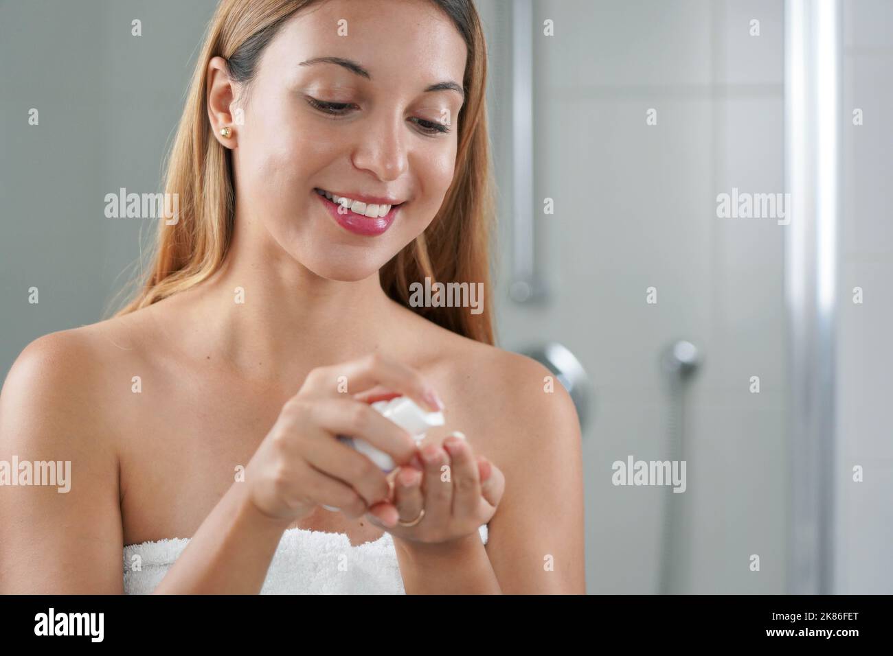 Soins de la peau femme appliquant de la crème avec des anti-signes de rétinol dans la salle de bains Banque D'Images