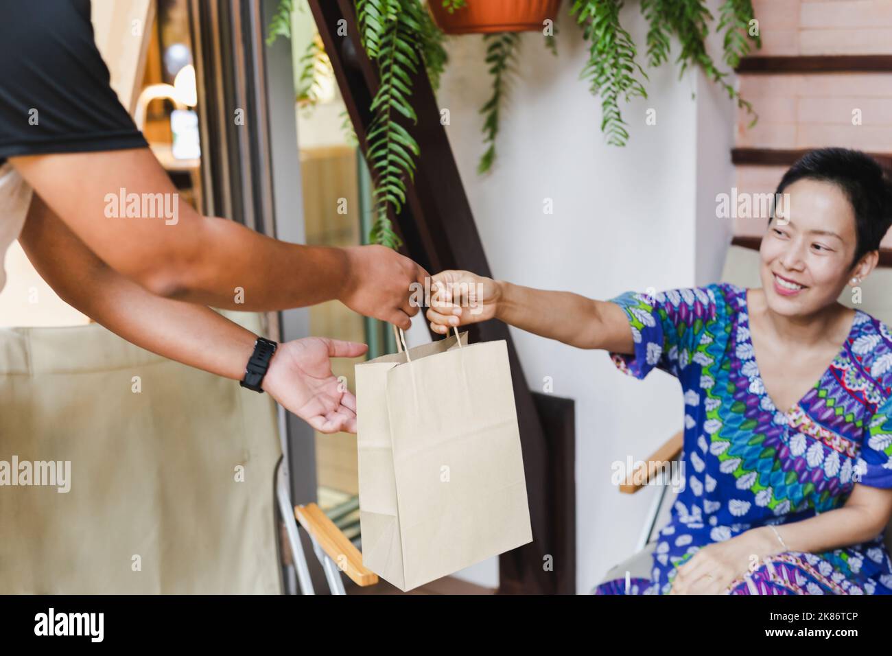 Serveur Focus sélectionné offrant un sac en papier écologique aux clients à emporter dans un café à l'extérieur. Banque D'Images