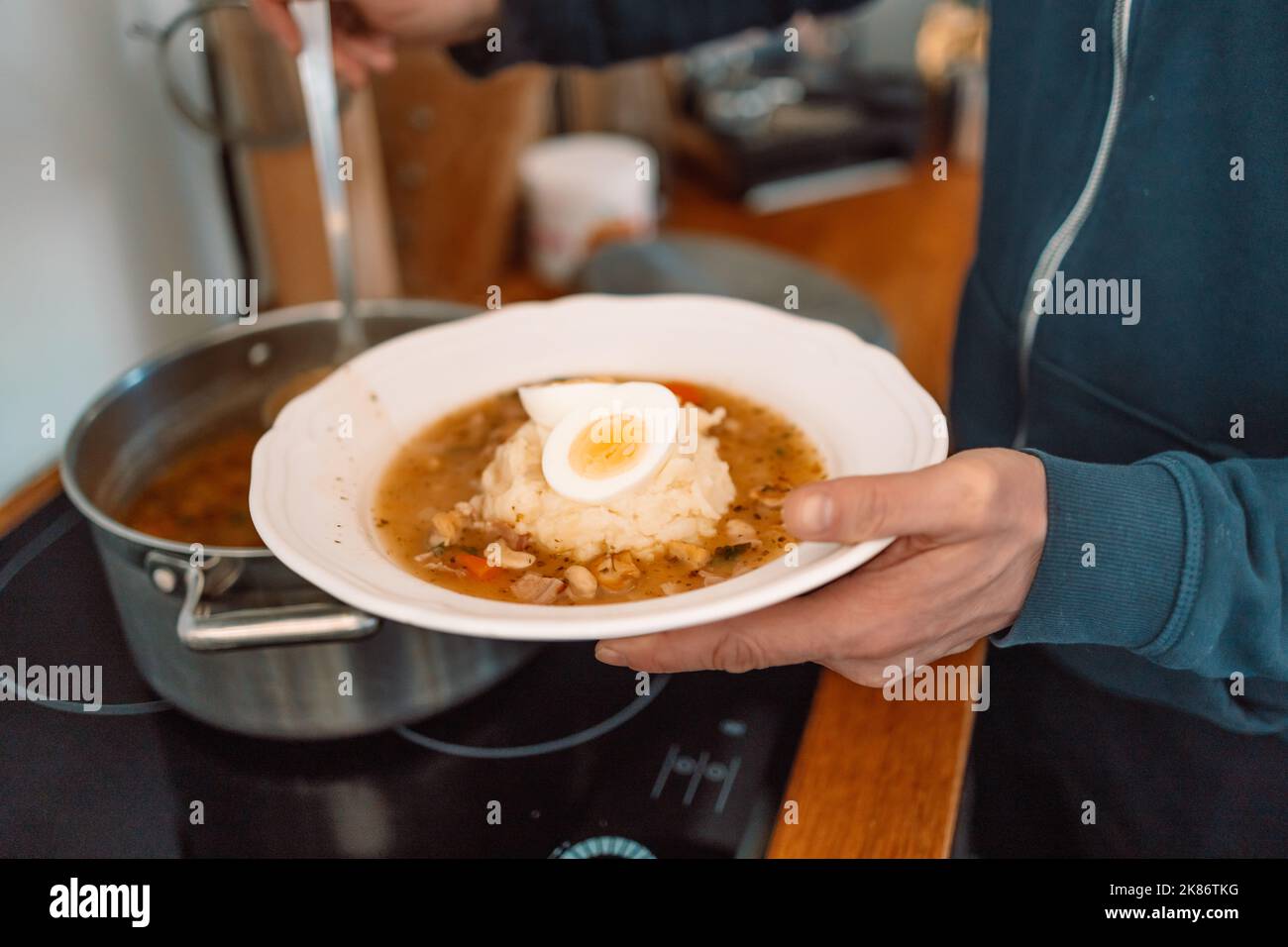 Soupe aigre traditionnelle polonaise Zurek dans un bol en céramique. Homme versant de la soupe dans un bol Banque D'Images