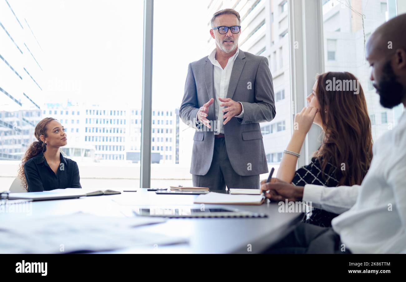 Plutôt mourir sur mes pieds que de vivre sur mes genoux. Un groupe d'hommes d'affaires ayant une réunion dans un bureau moderne. Banque D'Images