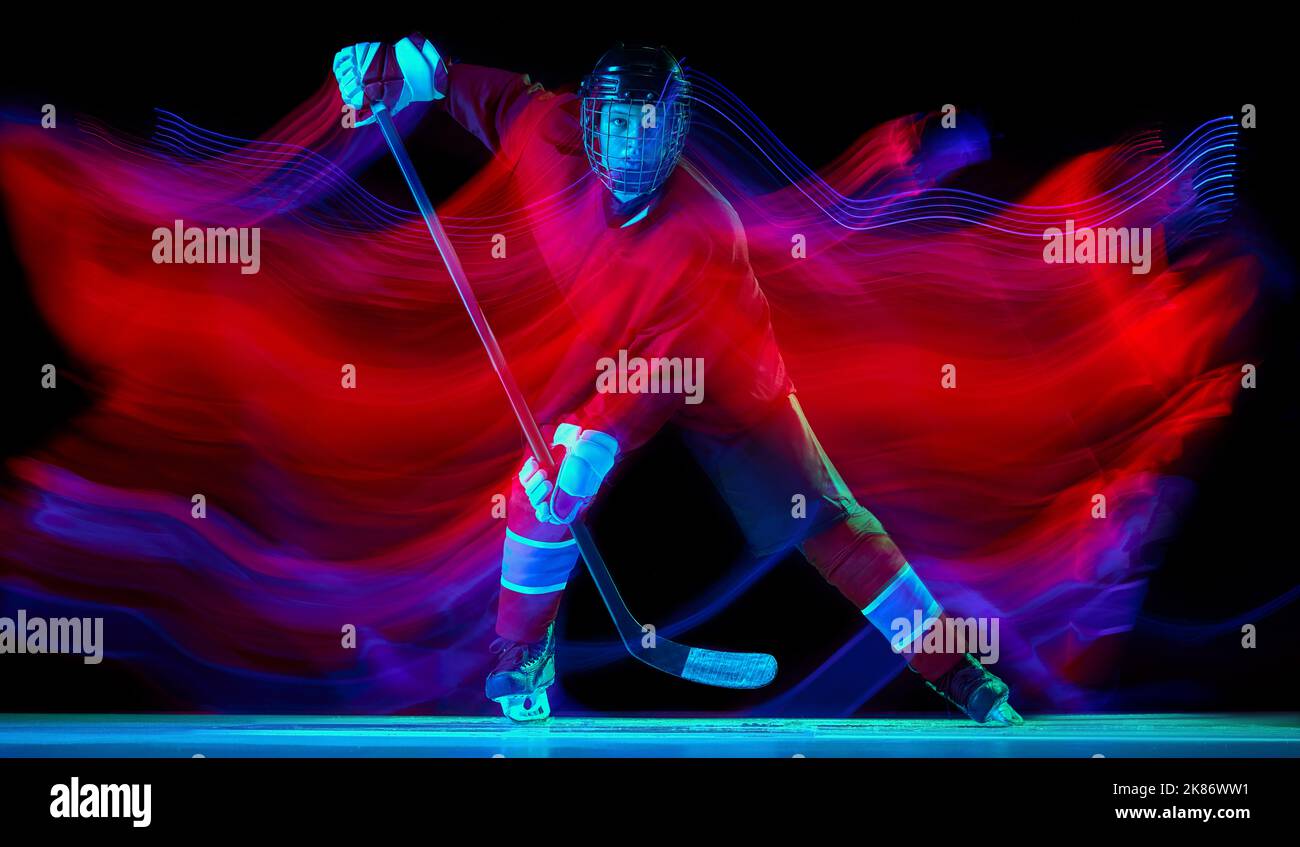 Portrait dynamique de l'entraînement énergique des joueurs de hockey avec bâton de hockey isolé sur fond sombre dans un néon mélangé. Art, sport, action, mouvement Banque D'Images