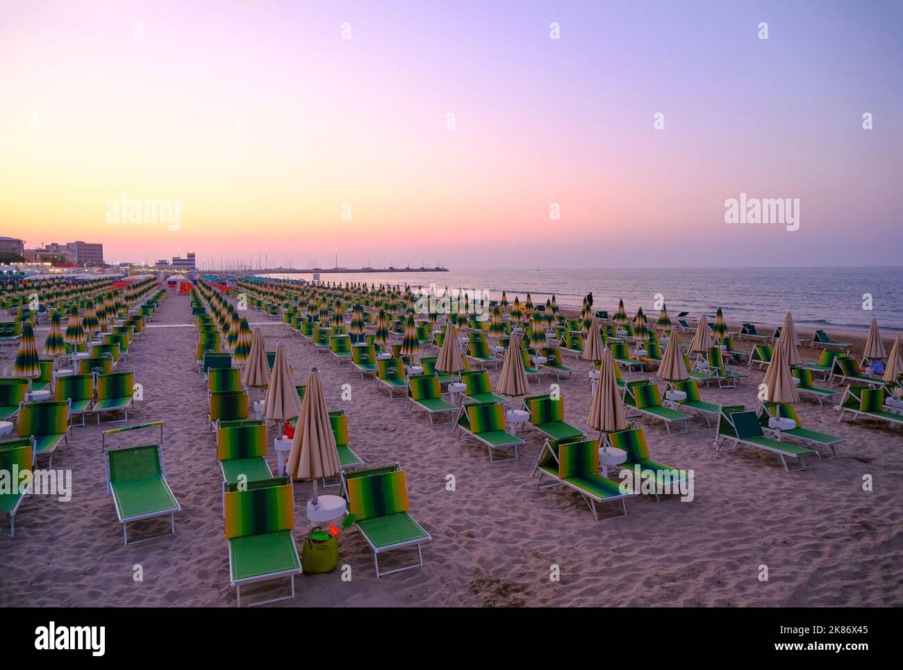 parasols et chaises longues sur la plage, face au coucher du soleil. Vacances d'été. Senigallia, Italie Banque D'Images