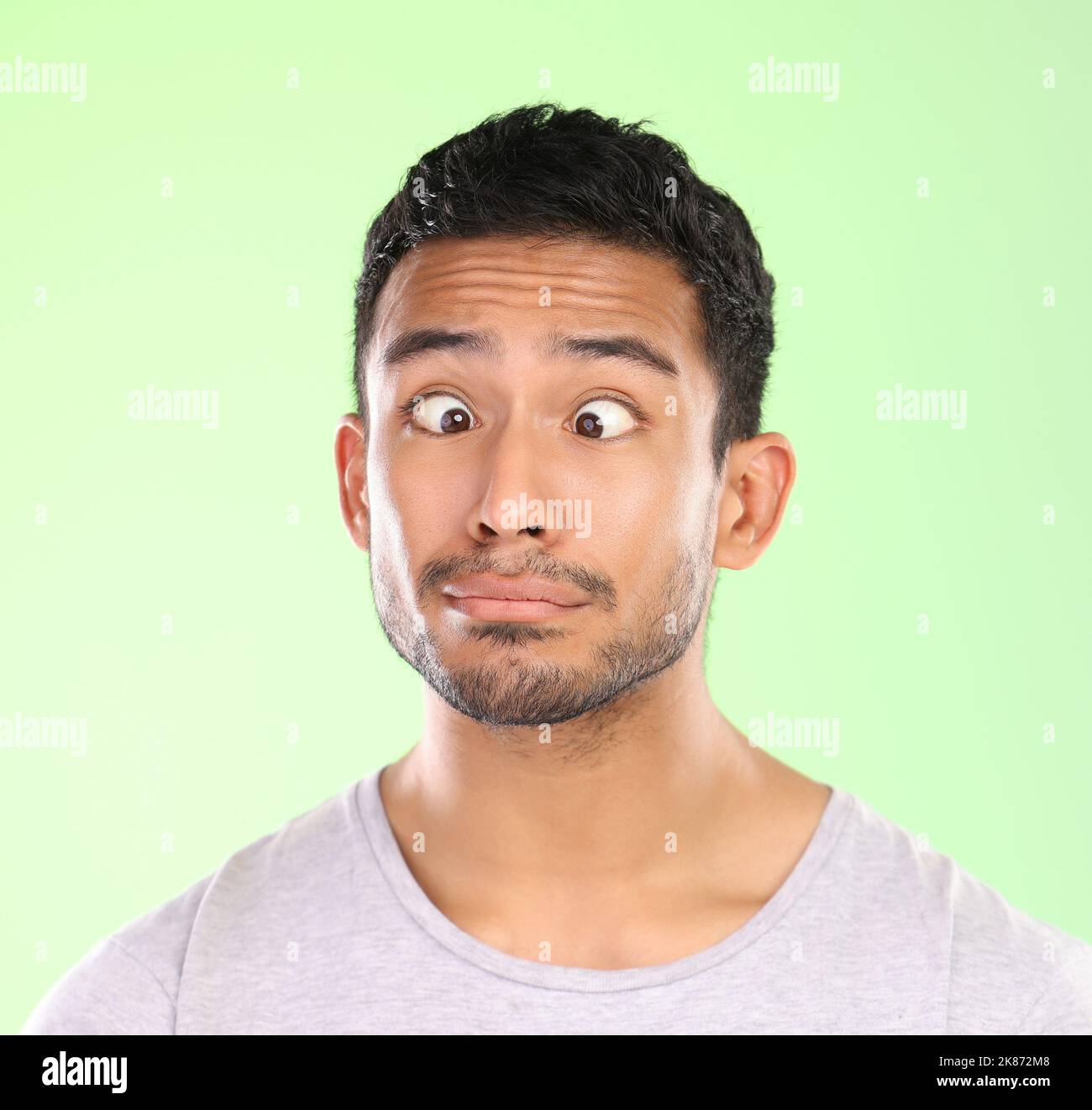 Quel goofball. Un beau jeune homme faisant un visage sur un fond vert en studio. Banque D'Images