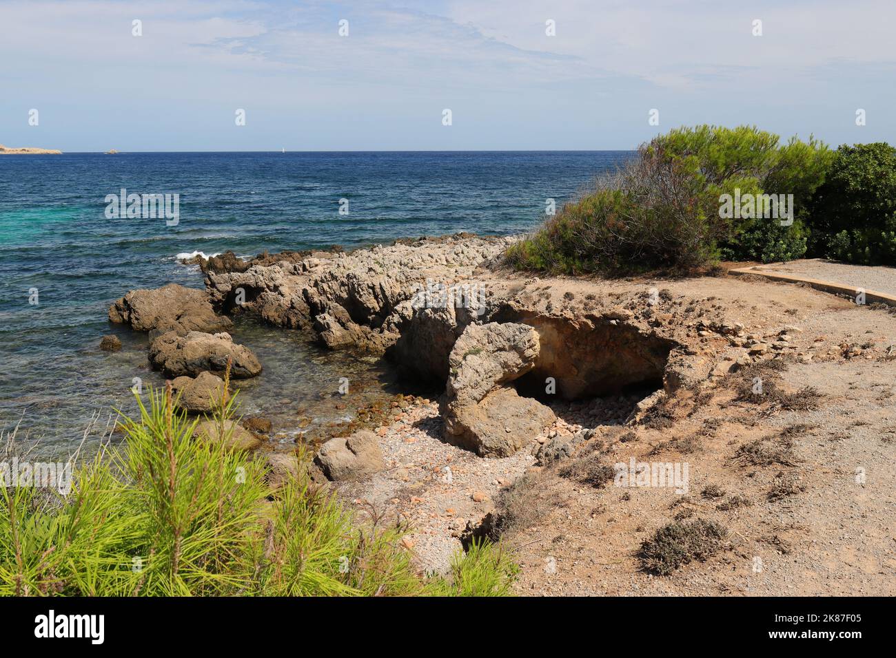 Vue idyllique d'une plage rocheuse avec végétation verte en premier plan et en arrière-plan, Cala Ratjada, Majorque Banque D'Images