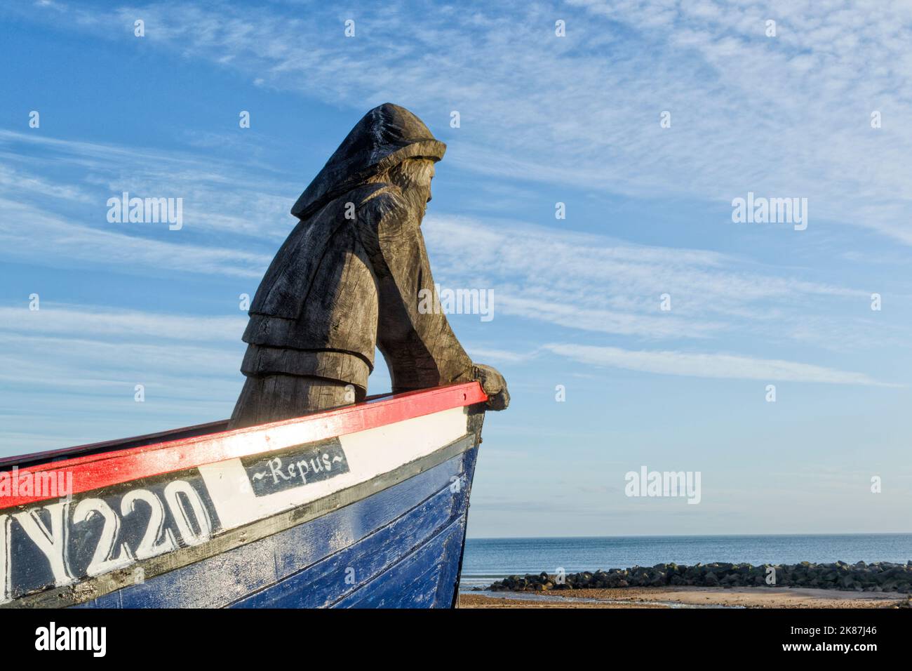 Le bateau Repus à Skinningrove. Un bateau de pêche ouvert restauré et équipé d'un pêcheur sculpté à la tronçonneuse à l'arc. Mémorial aux pêcheurs locaux Banque D'Images