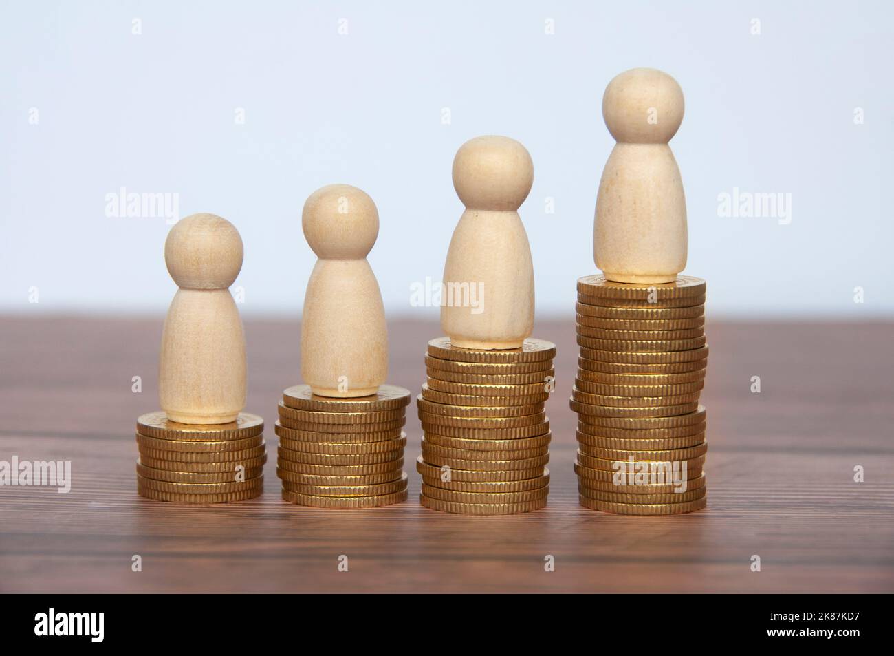 Les gens en bois figurent au-dessus des pièces en or. Réalisation des objectifs, croissance de l'entreprise et évolution de carrière. Banque D'Images