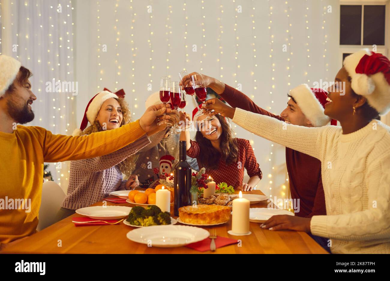 Des amis heureux et variés dînant ensemble à Noël Banque D'Images