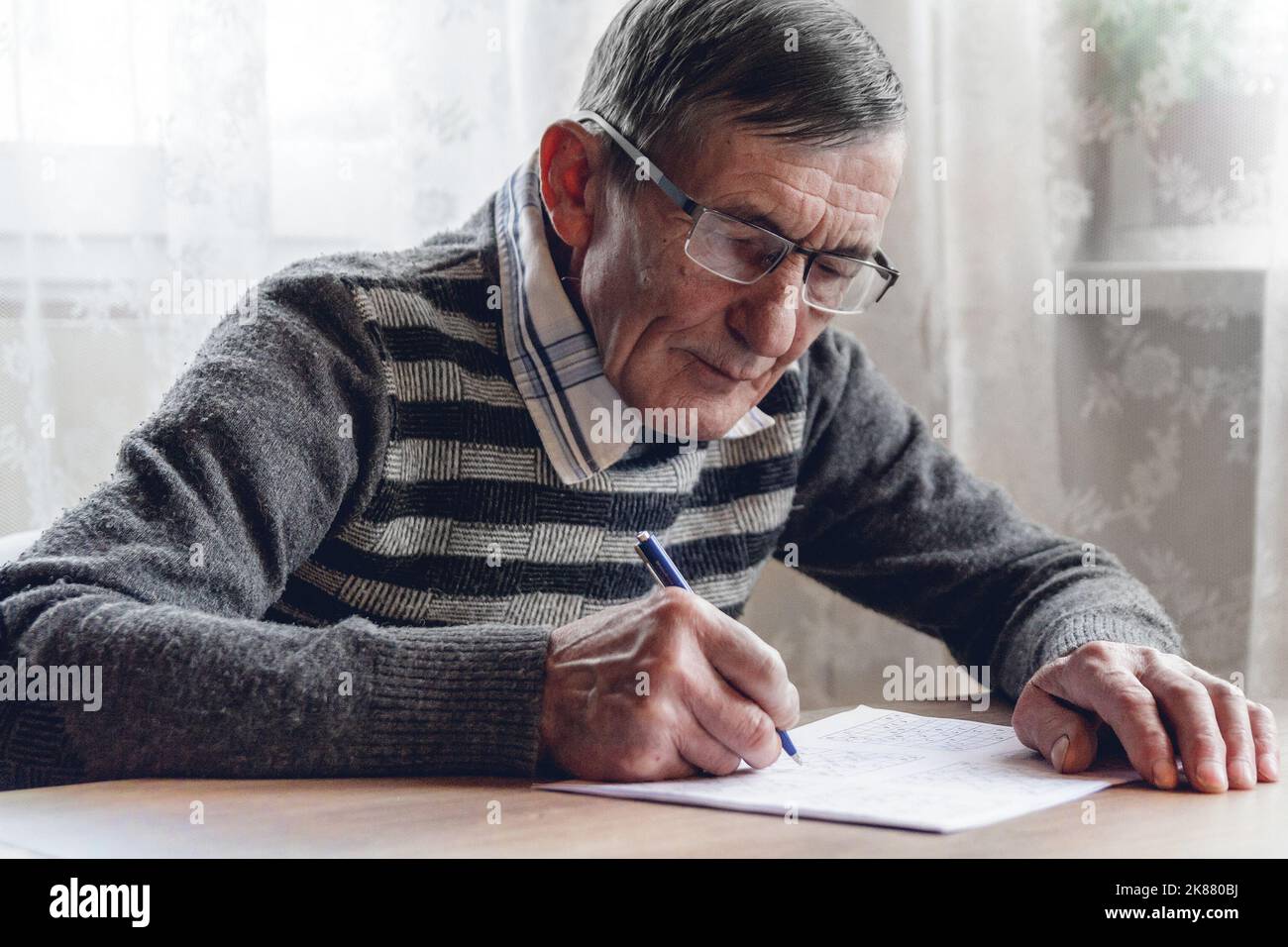 Senior résout le sudoku ou un casse-mots croisés pour ralentir le progressi Banque D'Images