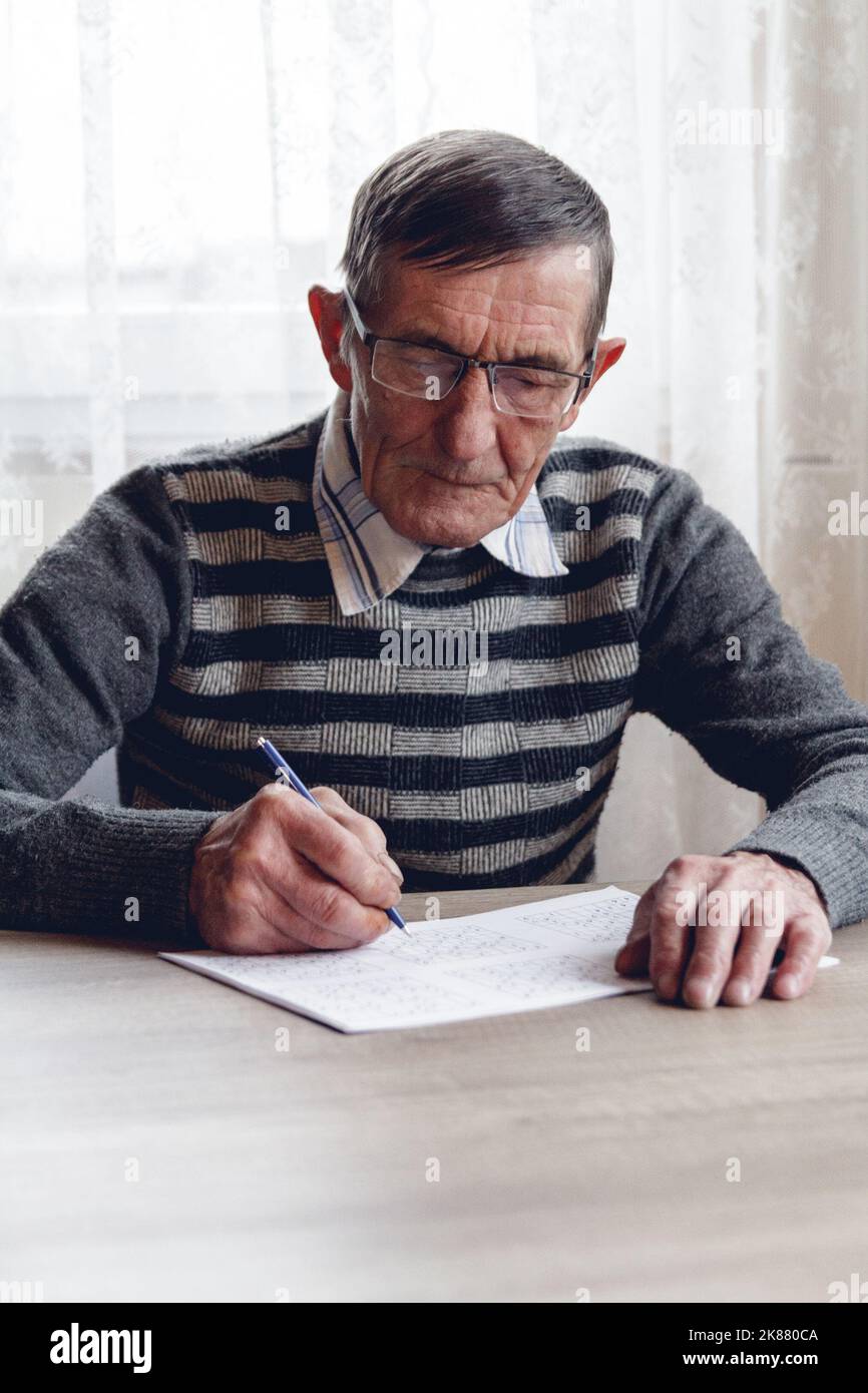 Senior résout le sudoku ou un casse-mots croisés pour ralentir le progressi Banque D'Images