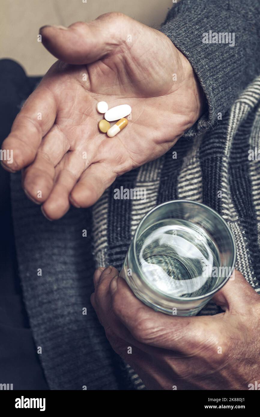Un homme âgé prend des pilules avec un verre d'eau Banque D'Images