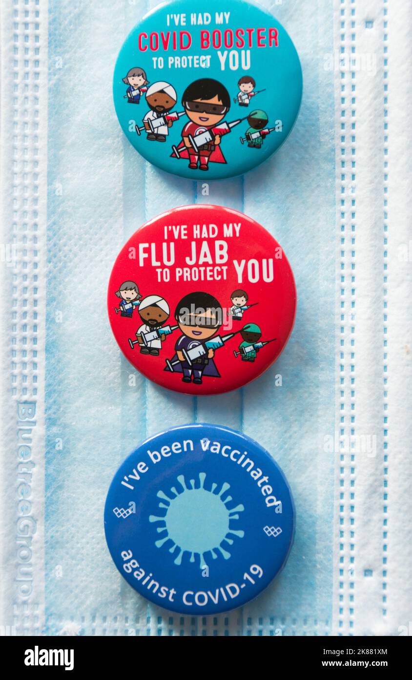 Badges colorés Covid 19 Booster et Flu Jab reposant sur un cordon NHS Banque D'Images