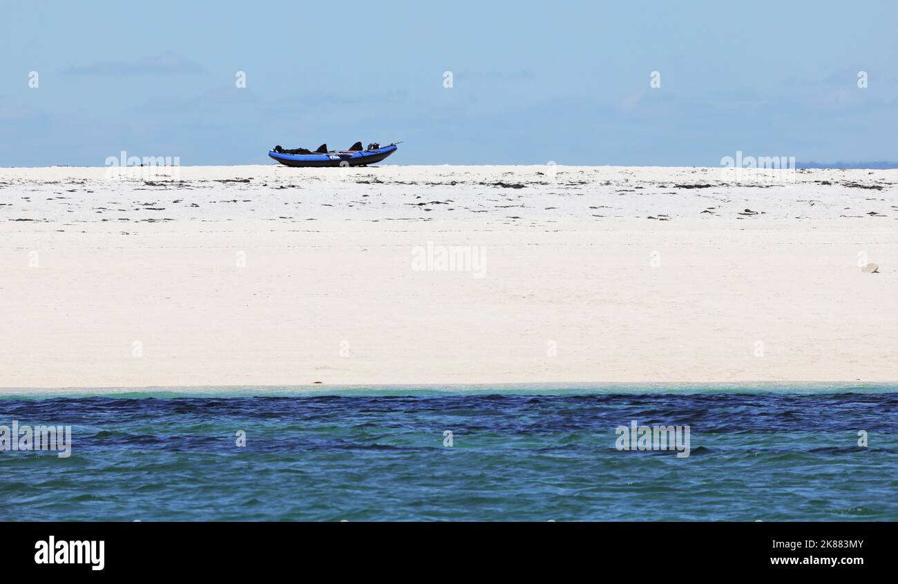Une vue panoramique d'un bateau gonflable sur une plage de sable au bord d'une mer bleue Banque D'Images