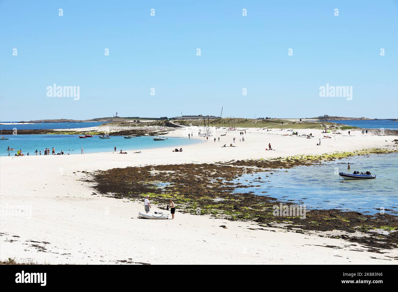 Un gros plan de personnes se détendant sur une plage de sable et se baignant dans une mer bleue Banque D'Images