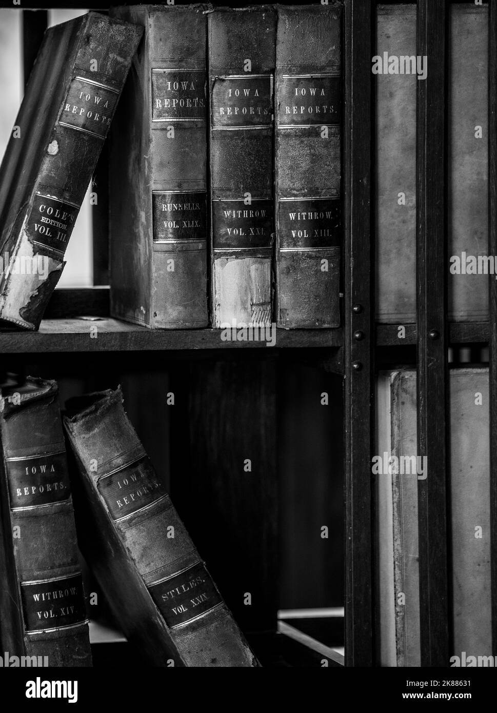 Une photo verticale en niveaux de gris de vieux livres historiques sur une étagère cassée Banque D'Images