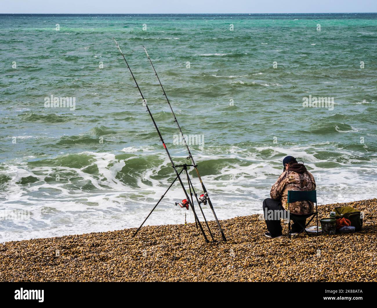 Un pêcheur solitaire sur la plage de Chesil à Dorset. Banque D'Images