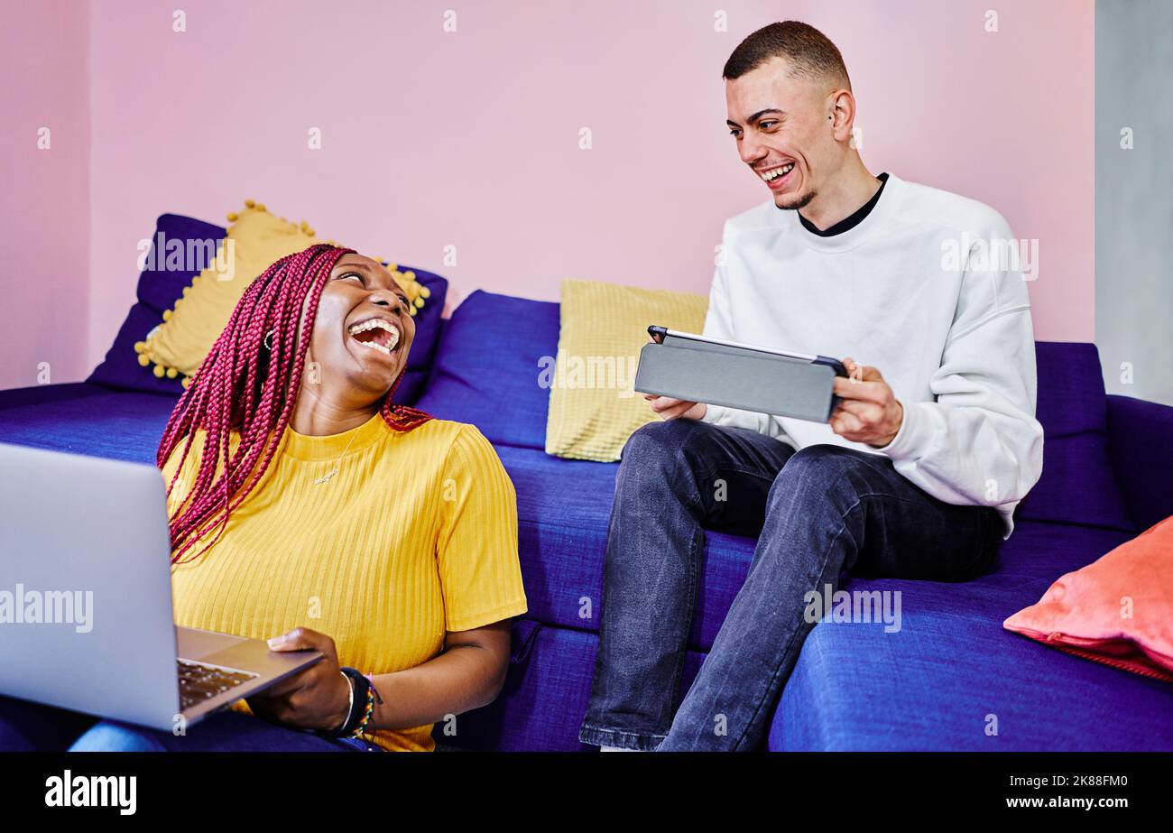 une femme riant à la blague pendant qu'elle fait ses devoirs avec une amie heureuse Banque D'Images