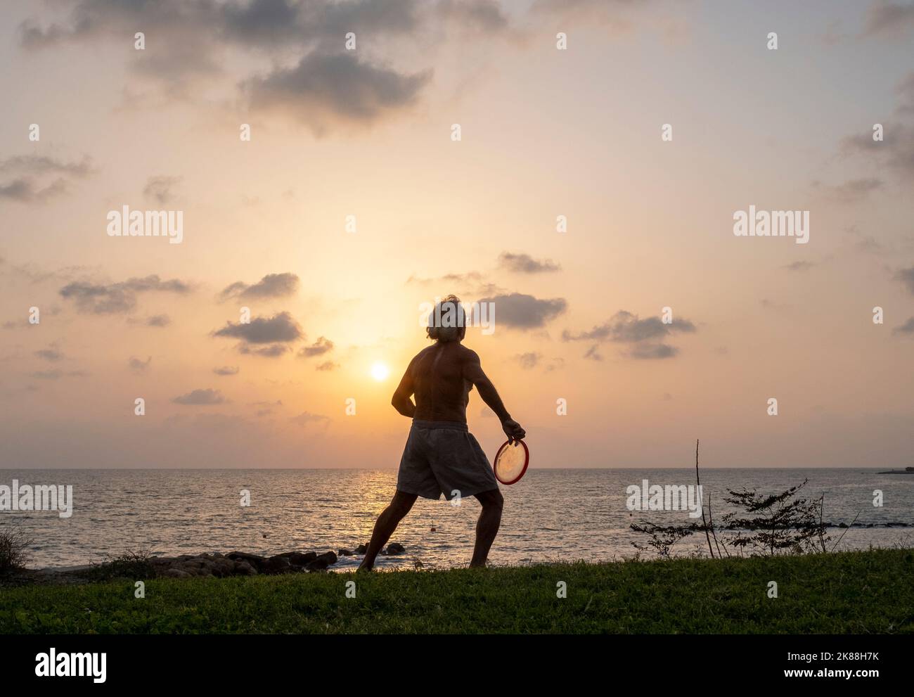 Un homme s'exerçant sur une plage qui jette une Frisbee, Paphos, Chypre. Banque D'Images