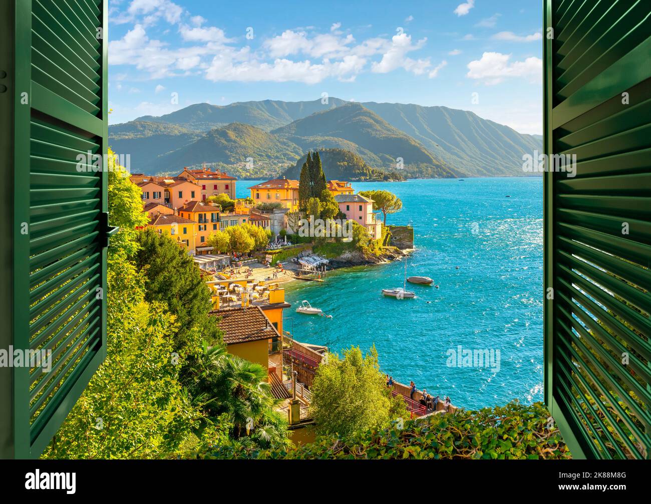 Vue par une fenêtre ouverte avec des volets donnant sur le village pittoresque et coloré de Varenna, en Italie, sur les rives du lac de Côme en été. Banque D'Images
