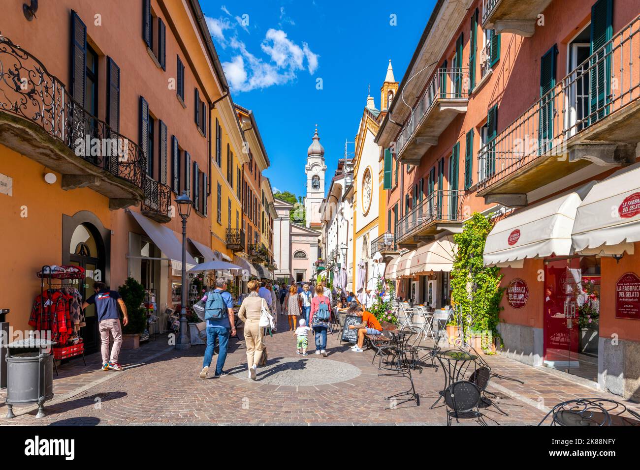 Une rue étroite et colorée de boutiques et de cafés dans la vieille ville médiévale de Menaggio, en Italie, sur les rives du lac de Côme. Banque D'Images